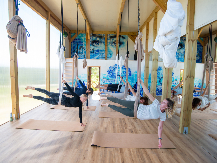 An aerial yoga class in Fuseta, with yogis practicing a fun pose